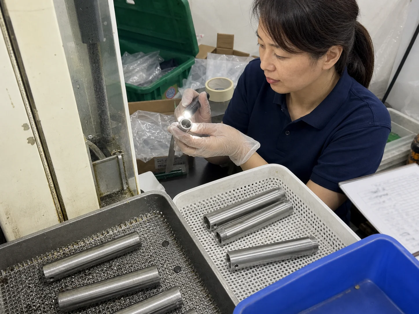 女性质量检验员在清洗工位检查SUS304传感器外壳盲孔残屑